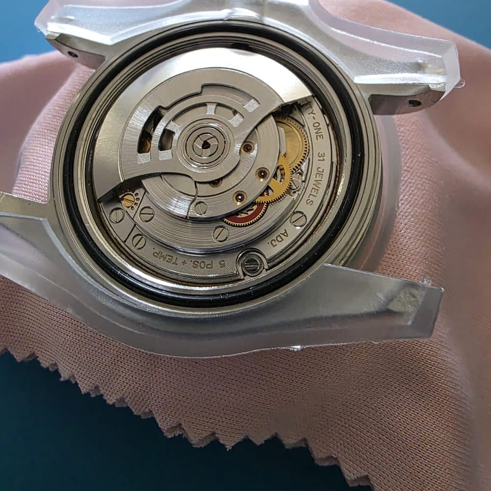 An automatic movement in an open caseback, held in a case holder on the bench